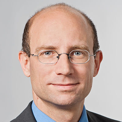 Headshot of Prof. Dr. Holger Patzelt, a man of mature age smiling on a simple light gray background.