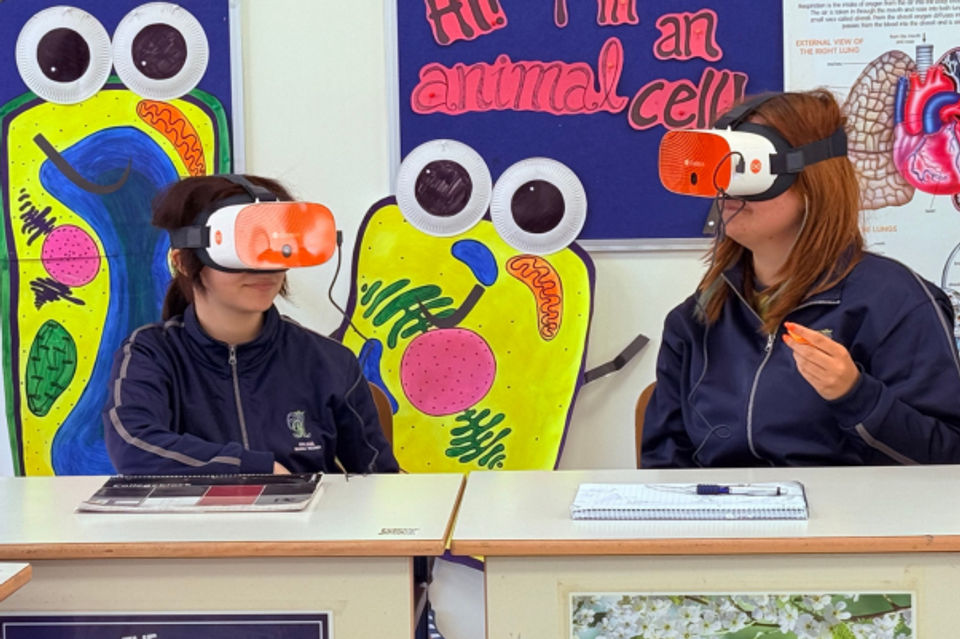 Two students sat at their desks, each wearing a VR headset