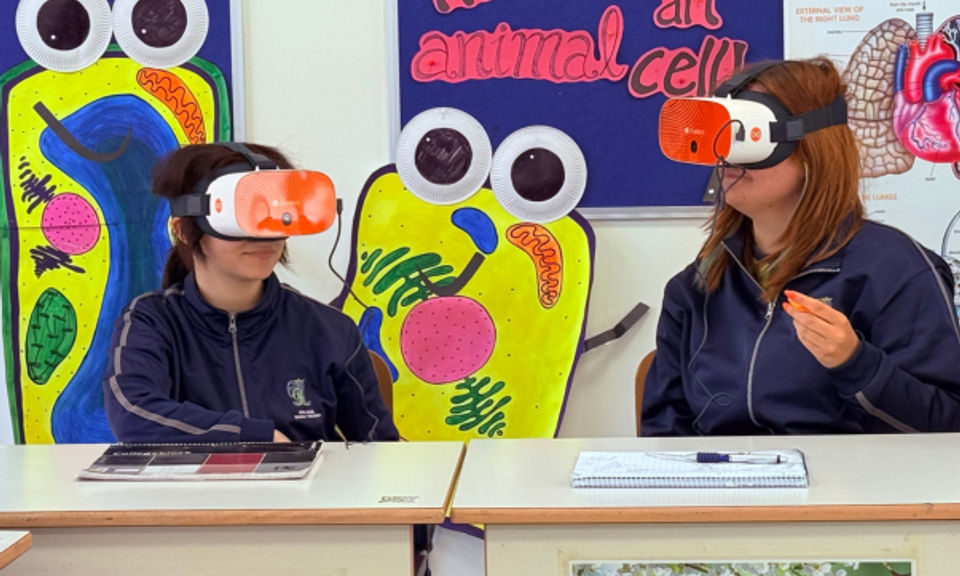 Two students sat at their desks, each wearing a VR headset