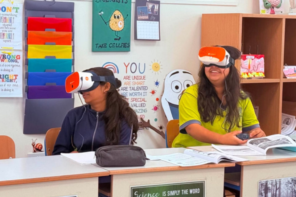 Two students sat at their desks, looking to their left whilst both wearing VR headsets