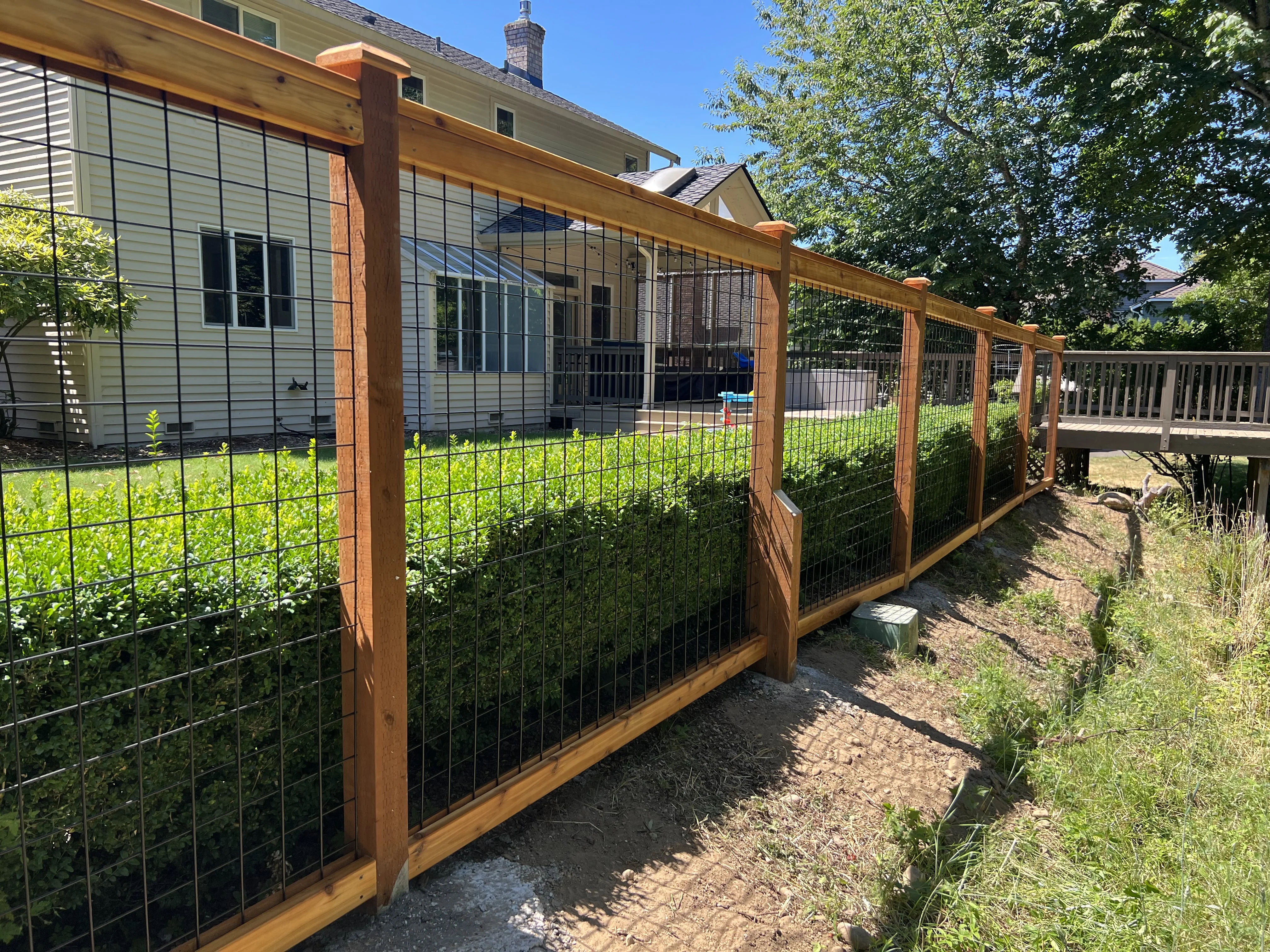 Black hogwire fence installed along residential property with cedar frame