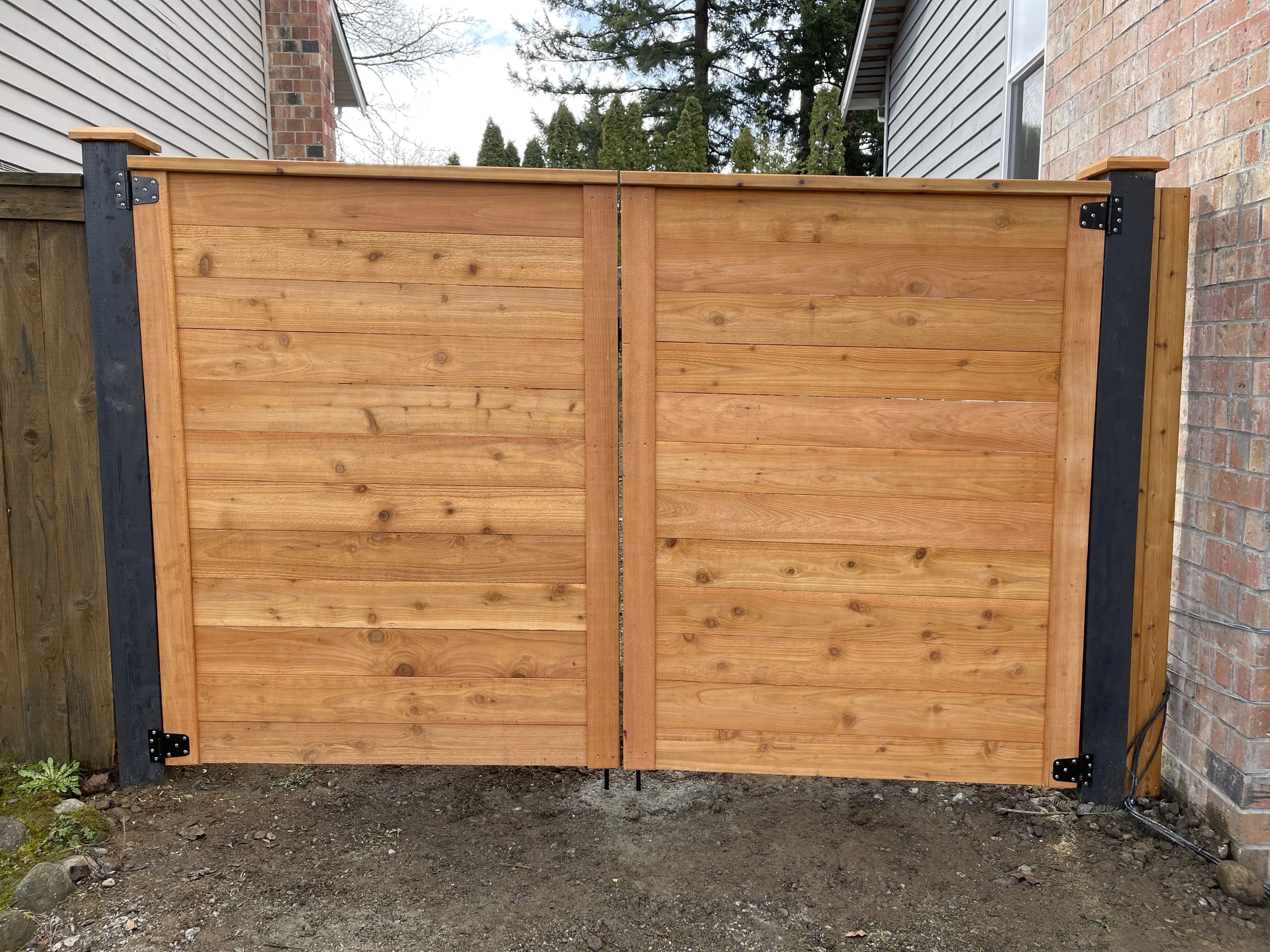 Horizontal cedar fence gate with black metal posts