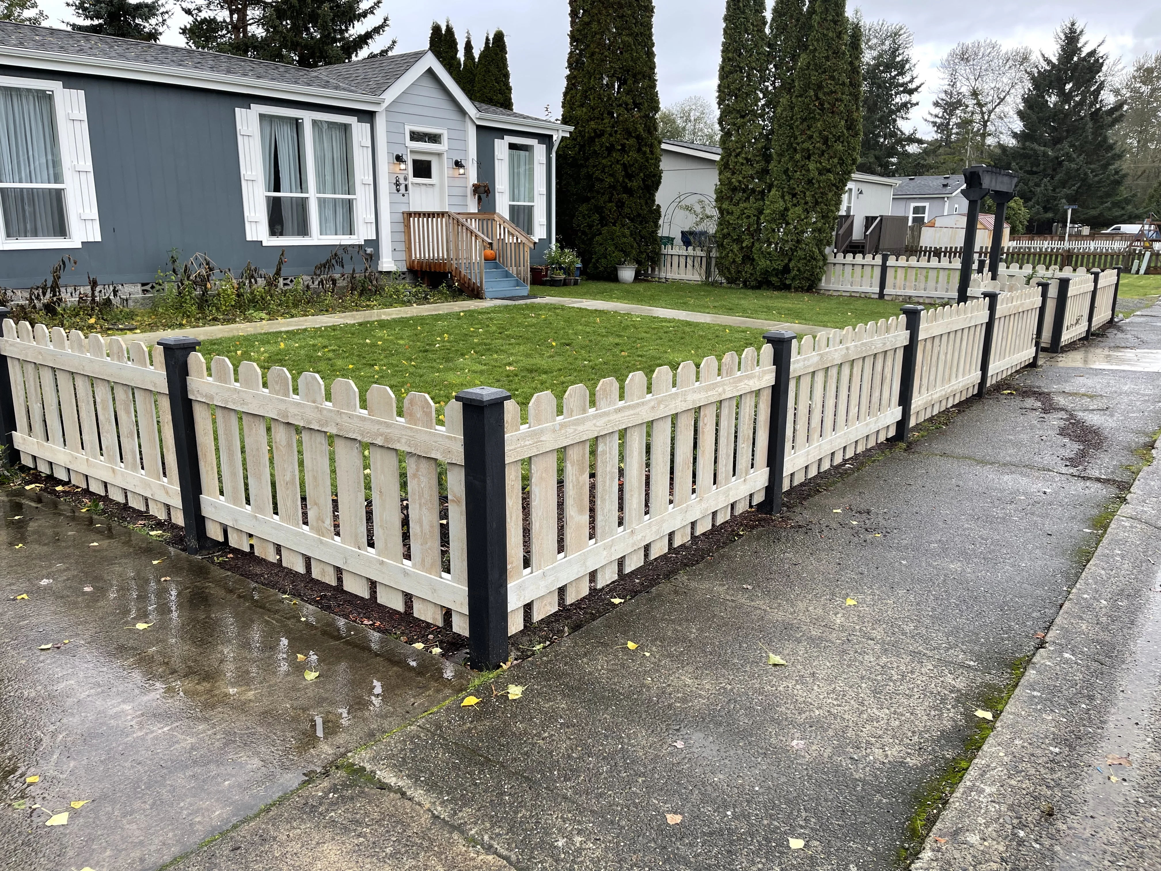 Traditional picket fence corner installation with black posts