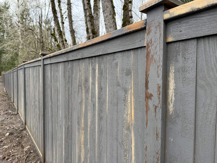 Fence panels with failed stain showing corrosion and flaking