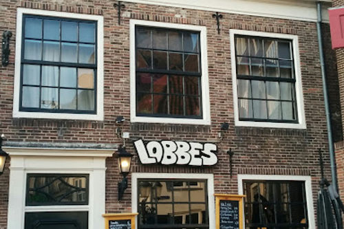 Café Lobbes historic brick building facade with large windows and outdoor seating area for live music performances.