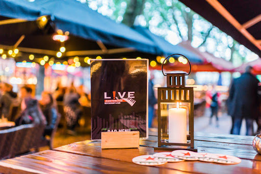 Live Amsterdam Pianobar outdoor venue with stage lighting, decorated tables, and festive atmosphere for live music performances.