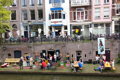 De Kargadoor waterfront bar with outdoor performance space, audience gathered along canal, Amsterdam.