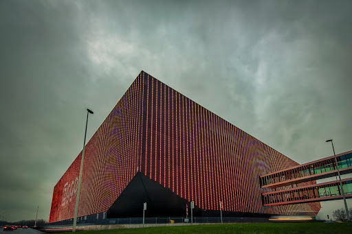 Ziggo Dome concert hall with distinctive red brick facade and modern architecture under dramatic cloudy sky.