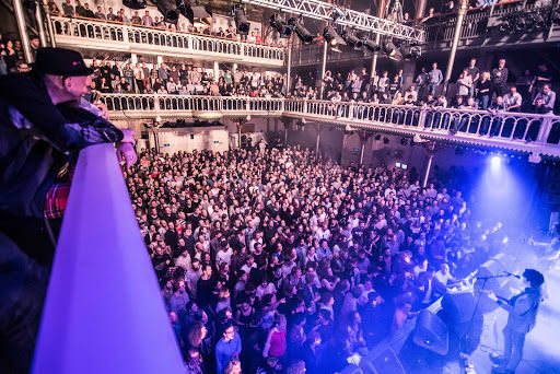 Paradiso concert hall packed with crowd under purple stage lighting and multi-level balconies.