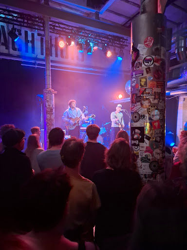 Live band performing at Slachthuis Haarlem with purple stage lighting, crowd, and professional sound equipment.