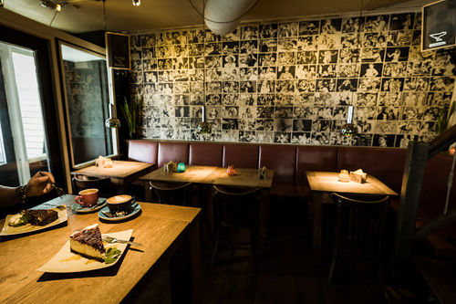 Café Tilt! intimate live music venue with booth seating, stage lighting, and photo-covered walls creating performance atmosphere.