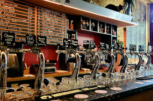 Kafé België bar with multiple beer taps, stage area, and warm lighting for live music performances.