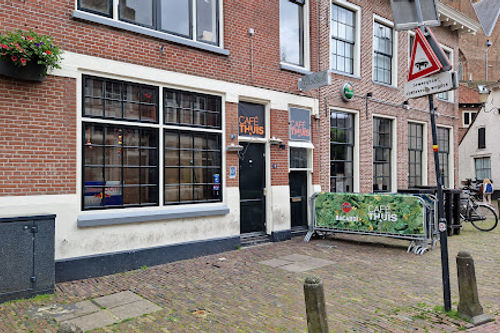 Cafe Thuis Amersfoort storefront with large windows and black doors on brick building, street-level live music venue.