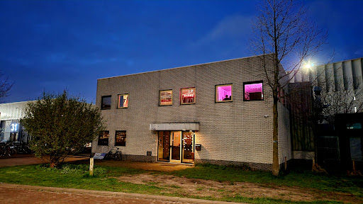Toekomstmuziek live music venue exterior at dusk with illuminated windows and brick facade.