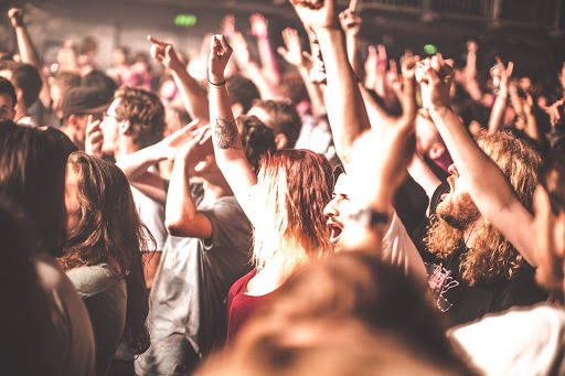 Melkweg concert hall with enthusiastic crowd with raised hands during live music performance under stage lighting.