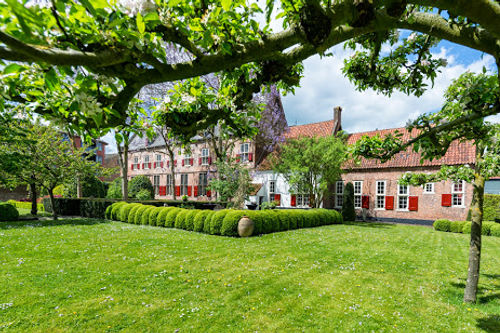 Mariënhof venue exterior with manicured lawn, historic buildings, and tree canopy providing outdoor performance space.