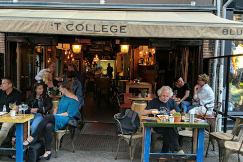 Cafe College blues bar exterior with patrons seated at blue tables outside the storefront entrance.