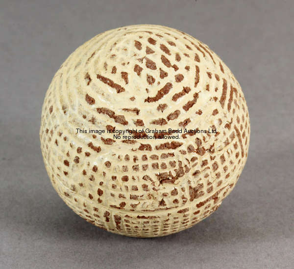 A hand hammered golf ball in red gutta percha, circa 1860, in reasonable condition