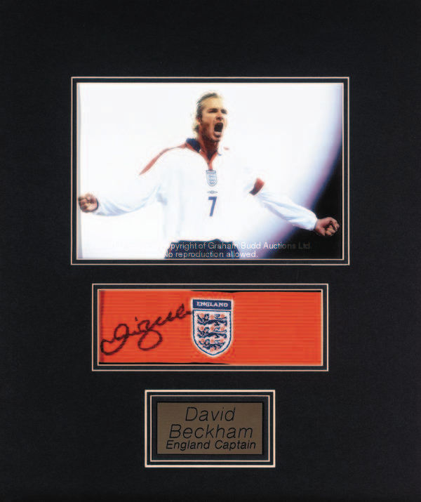 An England captain's armband signed by David Beckham, mounted between a colour photograph and a name...