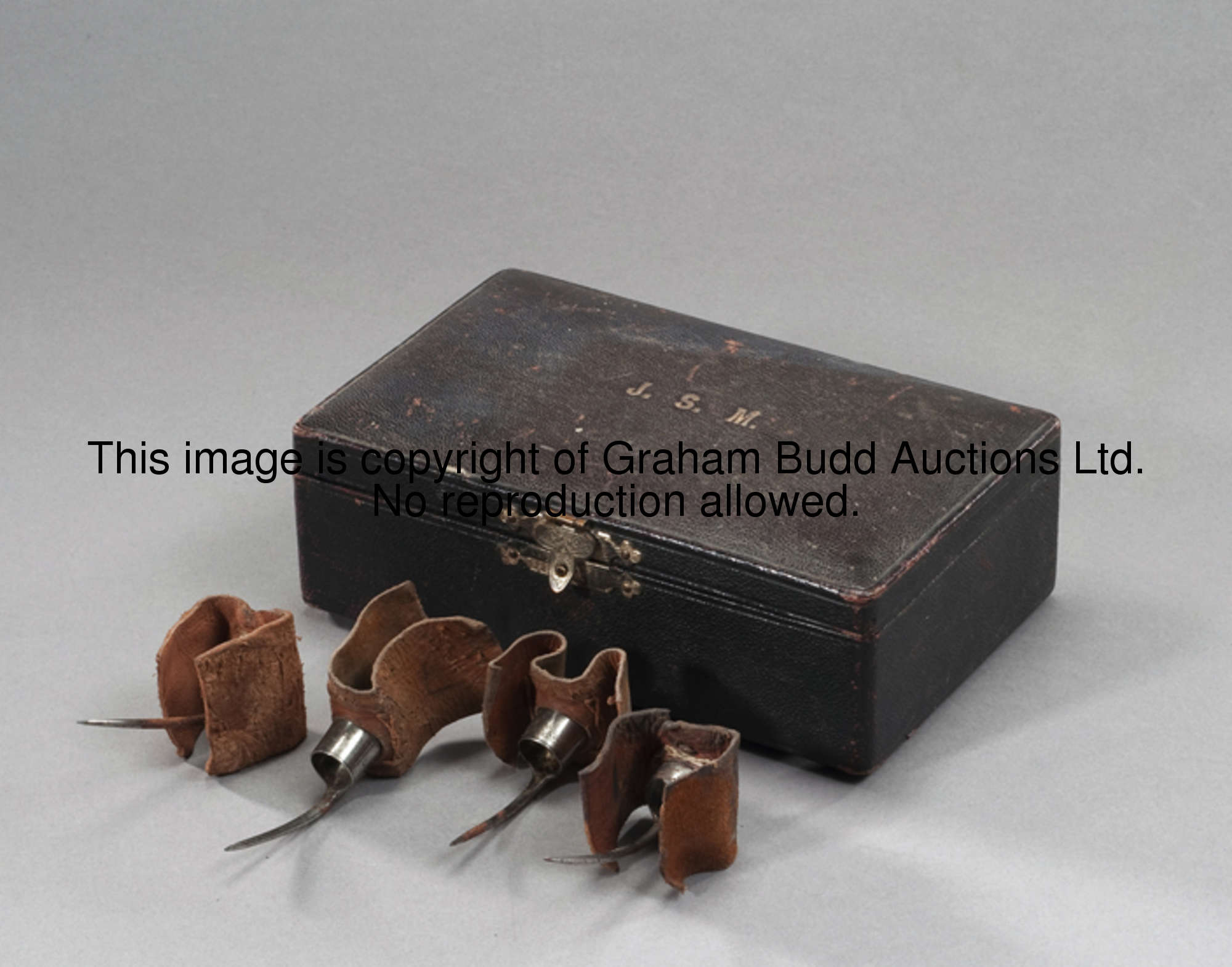 A boxed set of eight cock fighting spurs, the fitted box covered in leather with the lid stamped gil...