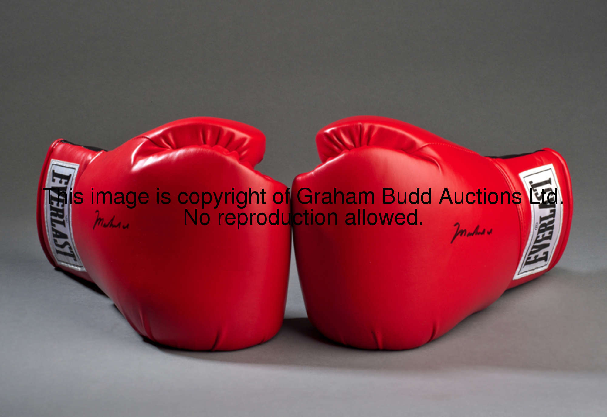 A pair of boxing gloves signed by Muhammad Ali, red Everlast gloves, both signed in black marker pen