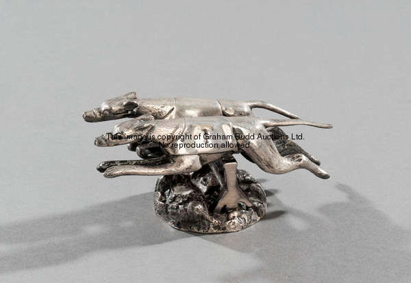 An unusual car mascot designed as two racing greyhounds taking a hurdle in unison, silver plated bro...