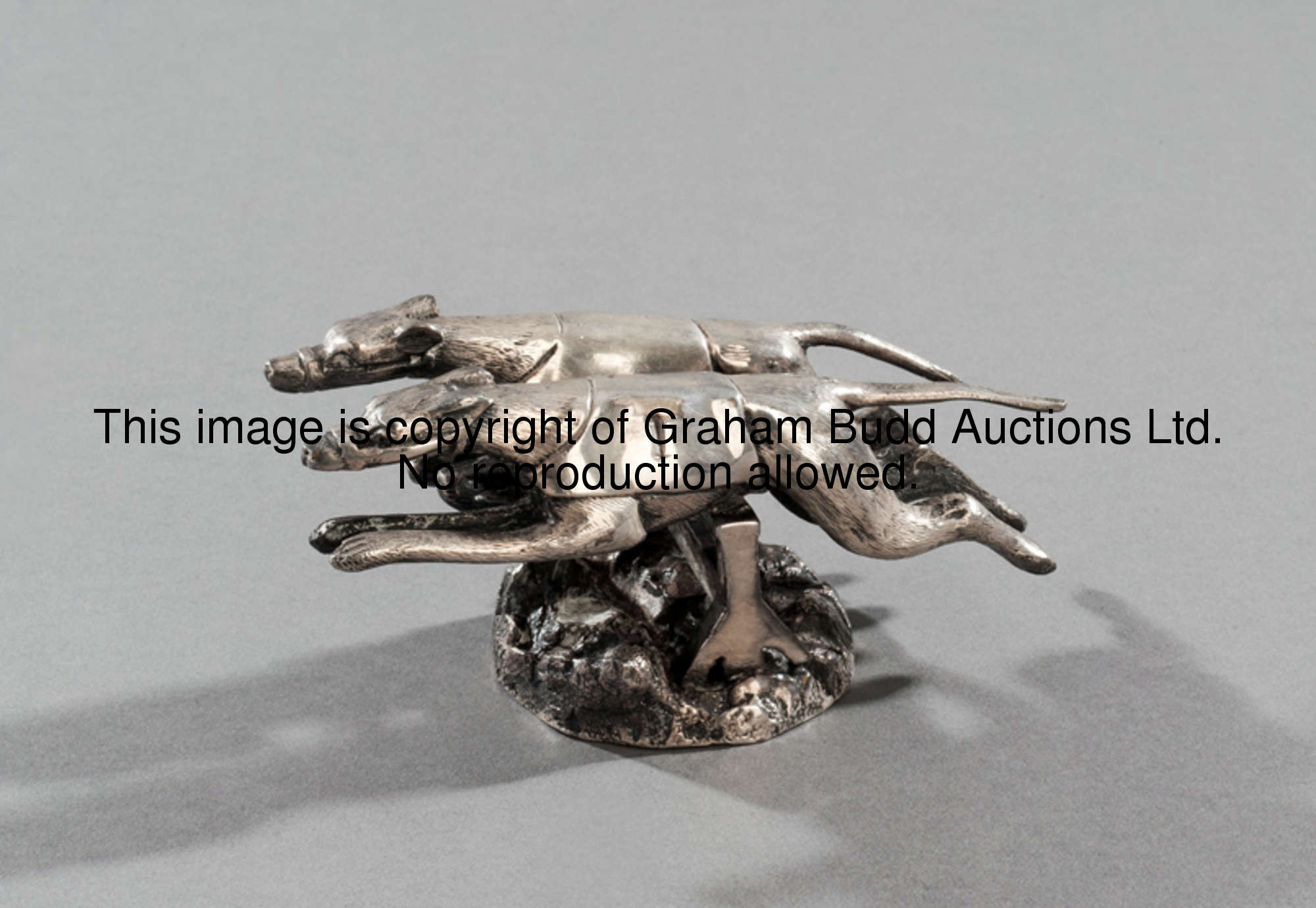 An unusual car mascot designed as two racing greyhounds taking a hurdle in unison, silver plated bro...