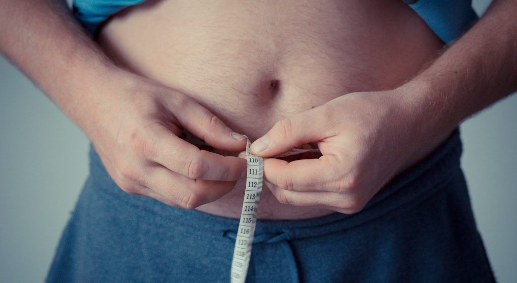 Overweight male measuring waist circumference