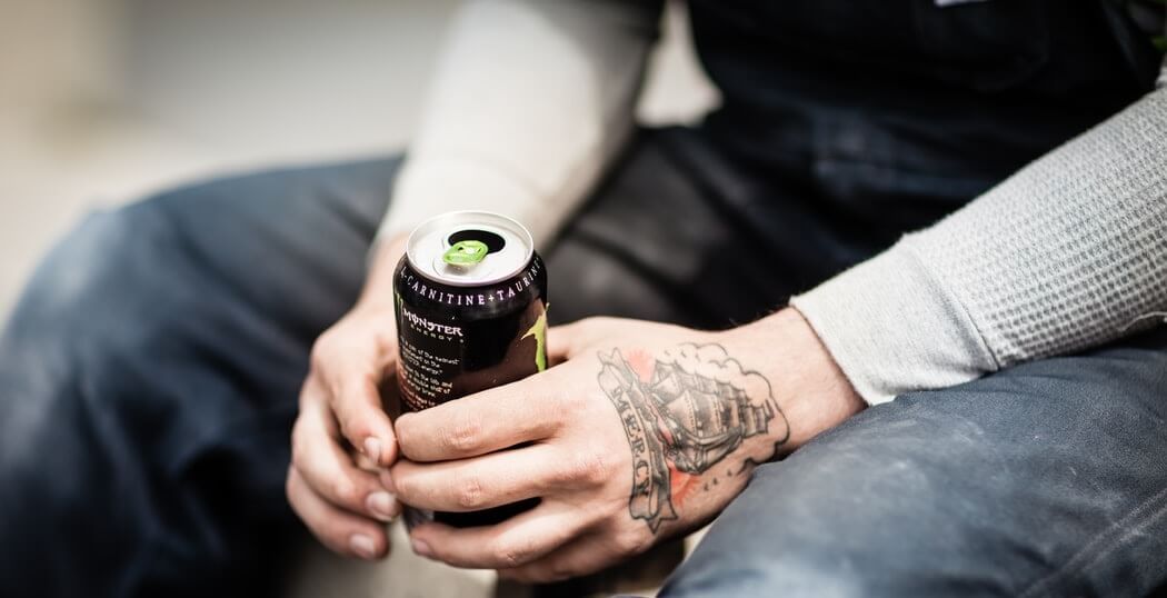 Tattooed man holding monster energy drink