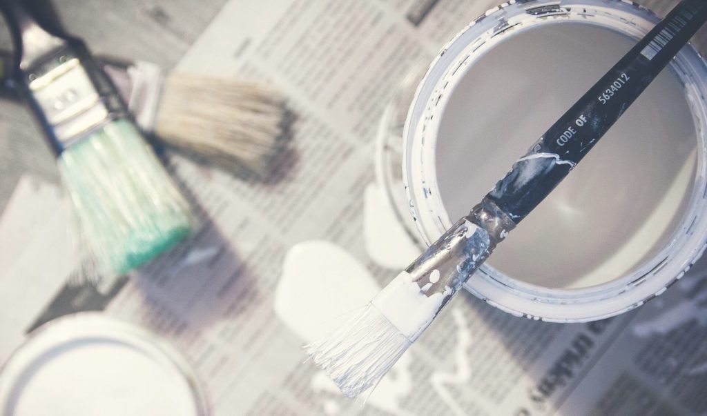 Tin of white paint with brush