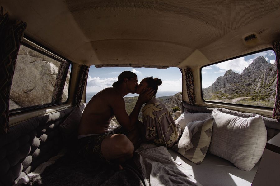 Couple kissing in a campervan with a mountain view in the background