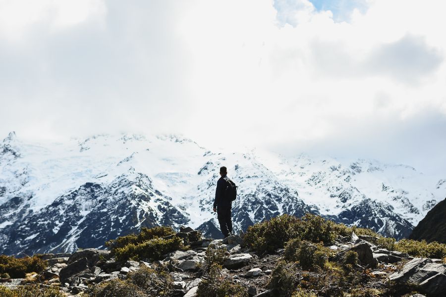 Hiker standing in front of mountain landscape.