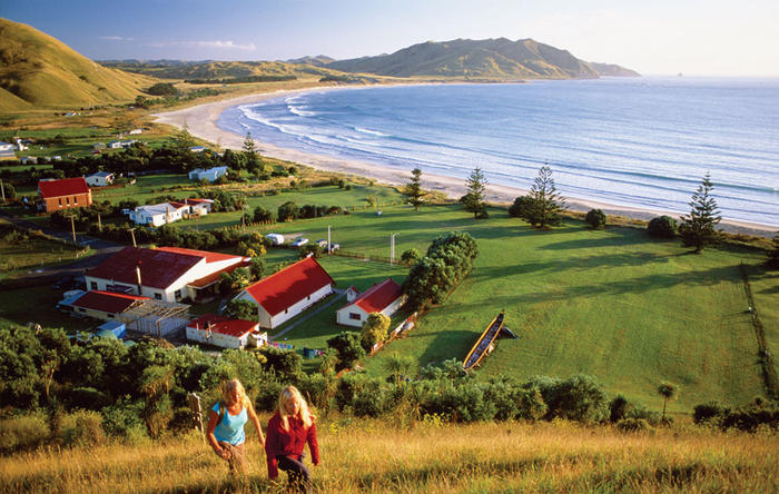 Couple hiking up a hill with a coastal village below