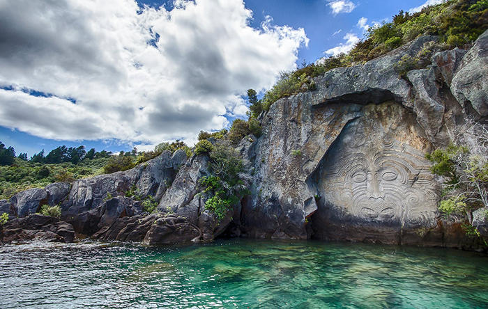 Large stone carving in a cliff face by a lake