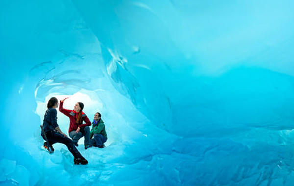 Group standing inside a blue ice tunnel