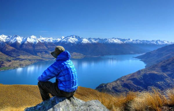 Man perched in a peak taking in a vast mountain landscape in New Zealand