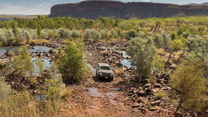 4WD vehicles travels along a rocky sectino of road in the outback