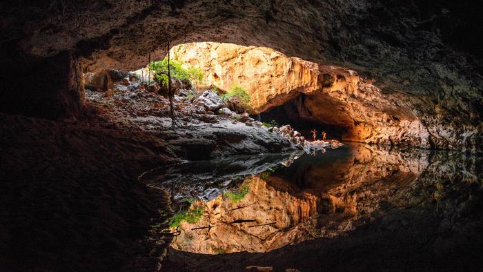 People standing in the entrance of a large cave formation