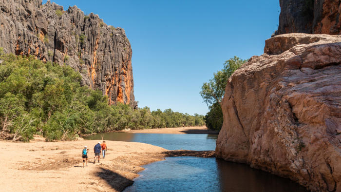 3 people hiking alongside a body of water in a gorge