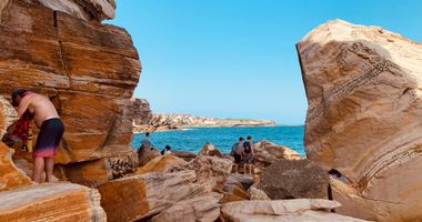 People standing on rocks by the water at Coogee