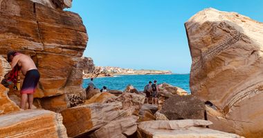 People standing on rocks by the water at Coogee