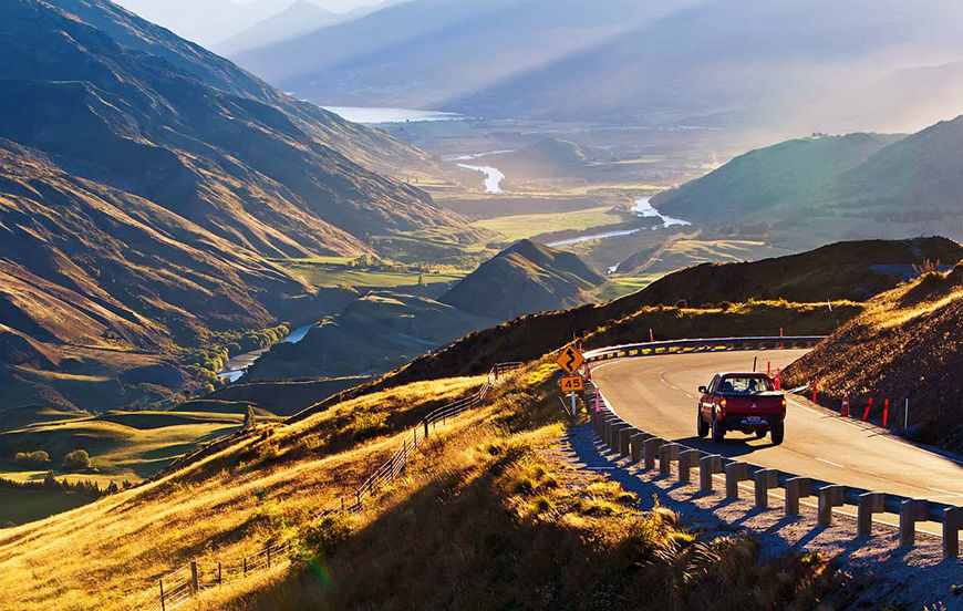 vehicle travelling down a mountain road bathed in sunlight