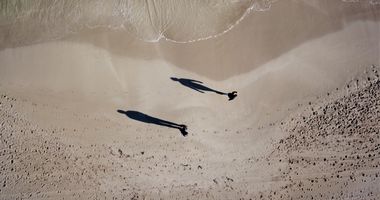 Top down view of 2 people standing at the water's edge on a Perth beach