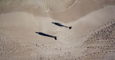 Top down view of 2 people standing at the water's edge on a Perth beach