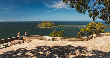 Couple sitting on ledge overlooking the ocean