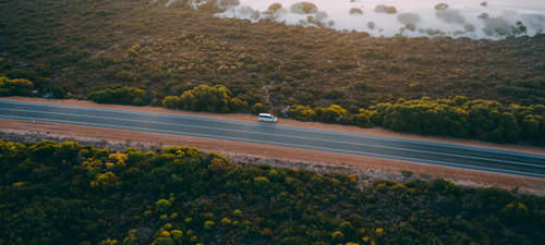 Aerial view of a campervan in a long stretch of Australian highway