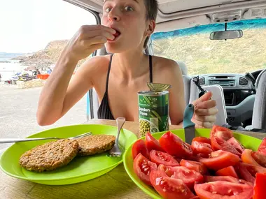 Traveller eating inside a Mystery Machine camper by the coast