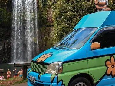Traveller on the Mystery Machine camper at a waterfall