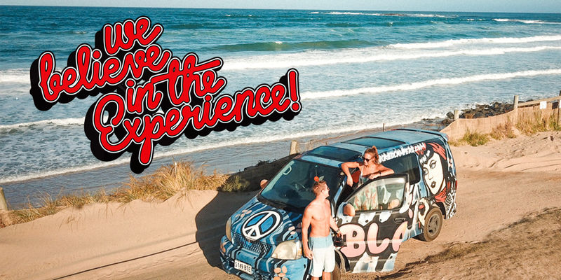 A colorful van covered in graffiti is parked on the side of the road. A logo with bold text reading 'We Believe in the Experience'