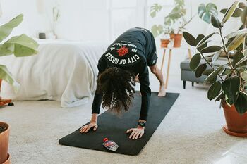 Person macht zwischen Zimmerpflanzen oga auf einer Yoga-Matte